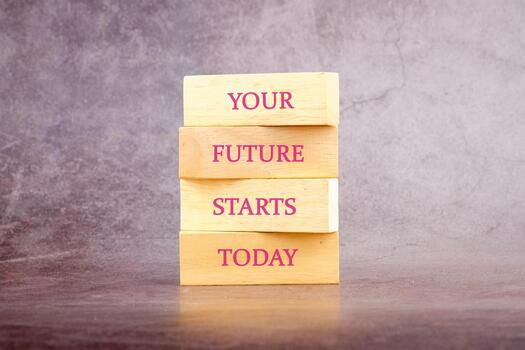A stack of wooden blocks sits on a textured surface, showcasing an inspirational message. Each block features a word that encourages individuals to take steps toward a brighter future now photo