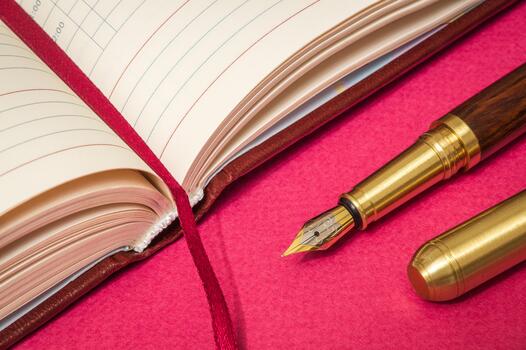 Office still life on red table with gilded pen and a notepad is preparing for the notes photo