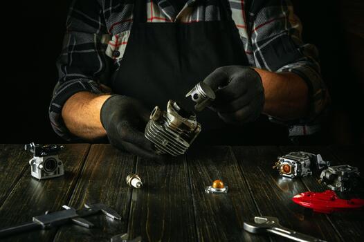 Engine repair service concept. The hands of a craftsman change the piston in the engine of a lawn mower on a work table in the workshop photo