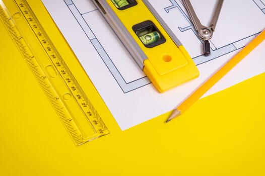 Accessories and drawing tools lie on building project or on the yellow working desktop photo