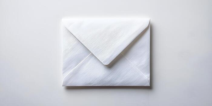 A plain white closed envelope lies flat on a simple light background creating a clean and minimalist image photo