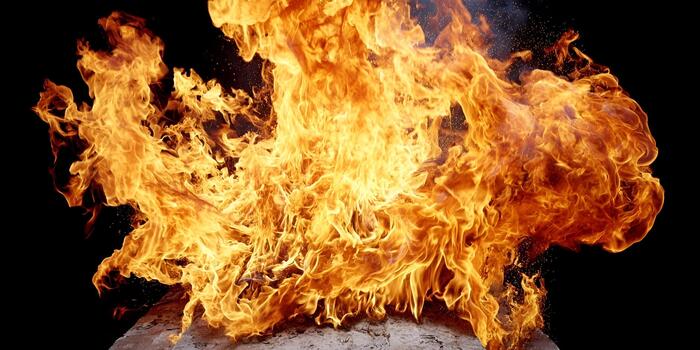 A powerful and dynamic fire bursts upwards with intense orange and yellow flames against a dark background photo