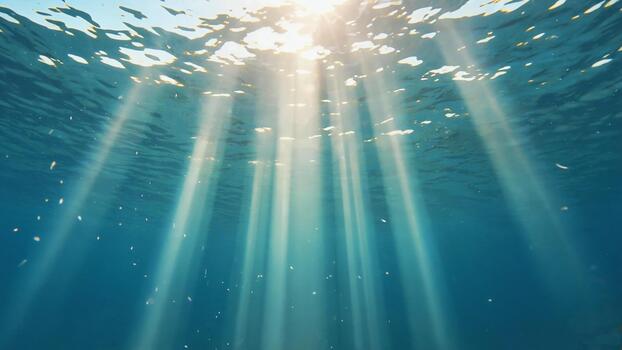 Sunlight streams through clear blue ocean water creating ethereal light rays and sparkling particles for a serene underwater adventure photo
