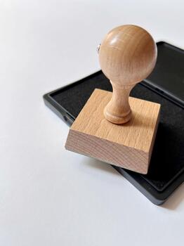 Wooden stamp with a round handle placed next to a black ink pad on white background photo