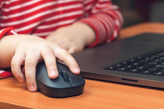 Child's hand holds a computer mouse, child learns and plays on the computer photo