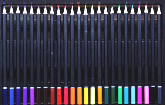 Top view of a complete set of colored pencils with black barrels, neatly arranged in a pencil case. The pencils are arranged in a color gradient, emphasizing symmetry, order, and color variety. photo