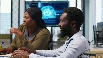 glad tekniker med handikapp och medarbetare chattar medan kodning ai algoritmer felsökning programvara frågor. optimistisk tech börja kontor den expert- i rullstol och kollega använder sig av dator, kamera en video