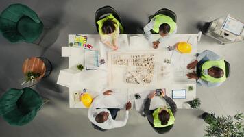 topo baixa Visão ampliação dentro do real Estado desenvolvedores e arquitetos dentro escritório revendo plantas e 3d modelos. desenvolvimento equipe discute urbano planejamento e propriedade investimento estratégias. Câmera uma. video