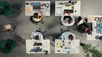 topo baixa Visão ampliação dentro do empregados colaborando em planejamento o negócio estratégia. colegas partilha mercado dados, desempenho relatórios e percepções, alinhando metas e recurso alocação. Câmera uma. video