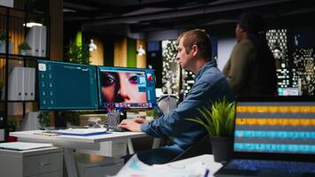 Male graphic designer using AI powered content for image retouching, working on contrast adjustments. Photographer employs futuristic interface for his portfolio, artificial intelligence. Camera A. video