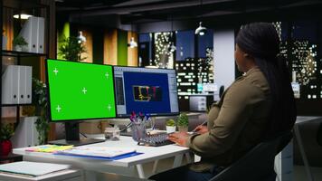 verde schermo Il prossimo per africano americano donna Lavorando su gioco sviluppando, utilizzando multiplo monitor a il ufficio. femmina ingegnere la creazione di un' futuristico navicella spaziale stazione su Software. telecamera un. video