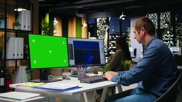 croma chiave con maschio dipendente Lavorando su gioco sviluppo, utilizzando doppio monitor a postazione di lavoro. giovane esperto ingegnere la creazione di futuristico navicella spaziale stazione su moderno Software. telecamera un. video