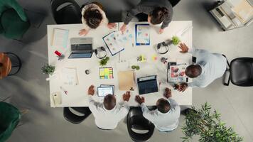 topo baixa Visão ampliação dentro do empregados discutindo o negócio intel e desempenho dentro reunião. multinacional companhia trabalhos equipe avaliações relatórios, previsões e diagramas para alinhar estratégia. Câmera uma. video