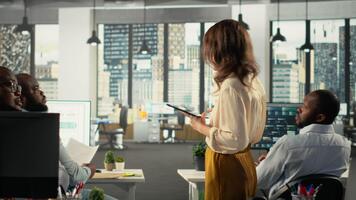 diverso colegas dentro uma multinacional companhia escritório discutir estratégia, gráficos e análise. corporativo equipe coordenadas projeto progresso, intuições e documentação para Melhor resultados. Câmera b. video