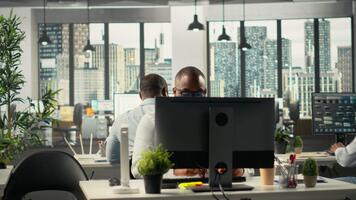 colegas de trabalho acionado dentro consultando e relatório partilha às ambiente de trabalho. profissional equipe avaliações visual dados e documentos para realçar o negócio estratégia e desempenho metas. Câmera b. video