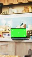 verticale verde schermo su il computer portatile nel il cucina con rustico contatore e elegante illuminazione. pentolame e utensili la creazione di un' confortevole e invitante domestico cenare spazio con moderno interno design. video