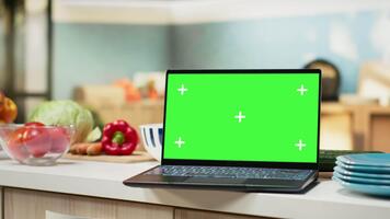 Green screen on laptop in the kitchen with rustic counter and elegant lighting. Cookware and utensils creating a comfortable and inviting household dining space with modern interior design. video