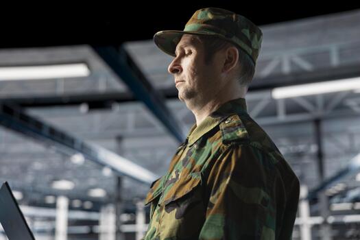 Army information technology expert in data center troubleshooting military computer systems and networks using laptop. Soldier in command center server room using notebook device photo