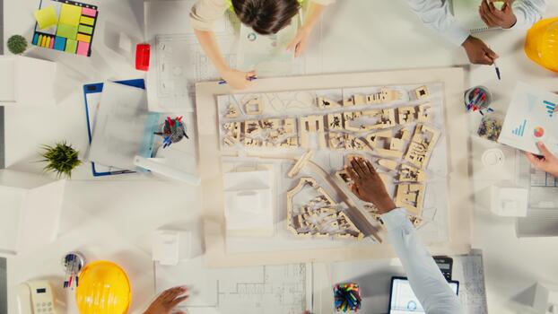 Top down view of developers and architects in business meeting reviewing blueprints and structural designs. Team discusses redevelopment and city planning for housing growth. photo