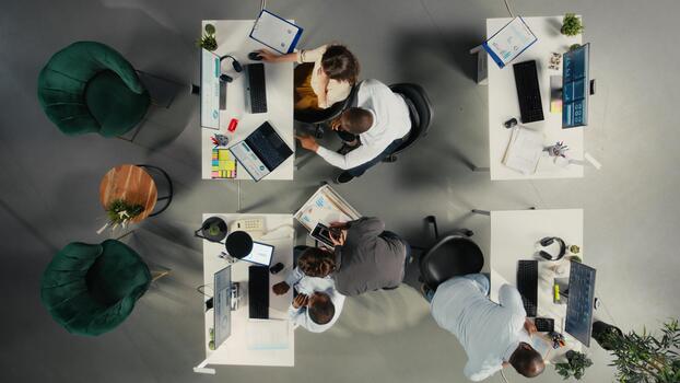 Top down view of employees reviewing charts and diagrams during briefing. Corporate team leads discussions on planning, documentation and report writing to enhance business intel. photo