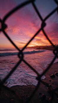 Sunset Over the Ocean Viewed Through a Chain Link Fence in a Coastal Area. photo