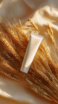 Soft Cream Tube Placed on Golden Wheat Stalks Against a Smooth Fabric Backdrop in Warm Afternoon Light photo