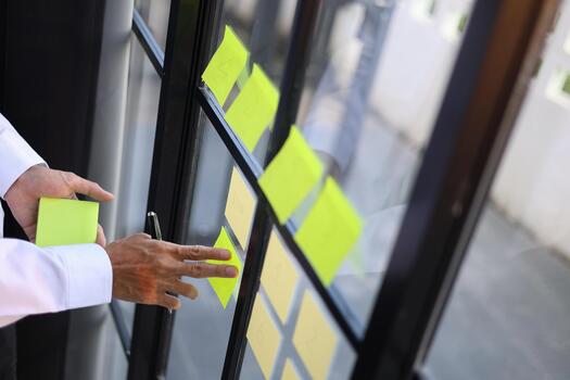 Businessman putting notes on mirror for organizing thoughts and planning tasks for project management and brainstorming. photo