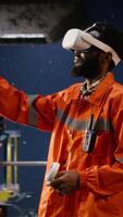 vertikal ingenjörer med vr glasögon på offshore olja plattform använda sig av virtuell verklighet tech till simulera borrning operationer och övervaka maskineri, säkerställa säkerhet protokoll i petroleum extraktion. kamera b. video