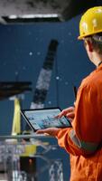Vertical Industrial worker on offshore drilling rig evaluates data for emission tracking, tablet technology to manage efficient fossil fuels extraction from the maritime environment. Camera B. video