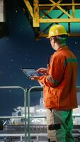 Vertical Industrial worker on offshore drilling rig evaluates data for emission tracking, tablet technology to manage efficient fossil fuels extraction from the maritime environment. Camera A. video