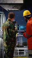 Vertical Military personnel and engineer work with AI tools on laptop, monitoring petroleum extraction and maritime patrol from offshore oil platform. Advanced deep learning solutions. Camera A. video