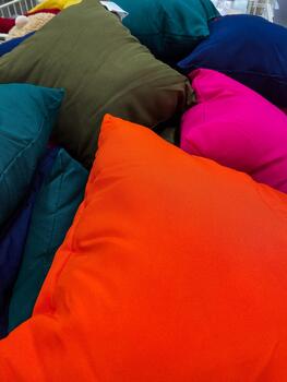 Bright orange and contrasting teal fuchsia cushions in store setup, Displaying assortment of lively colored pillows with textured fabrics and detailed stitching for marketing visuals photo