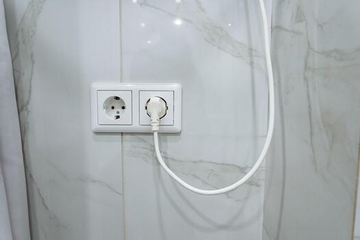 eléctrico enchufe con arrastrando cable, de cerca de lustroso losas destacando la seguridad y mantenimiento características, imagen capturar pulido mármol pared con eléctrico toma de corriente y la seguridad consideraciones foto