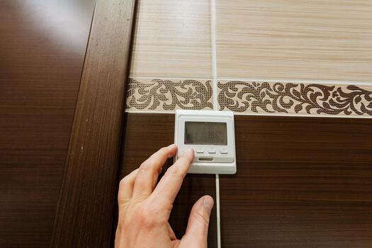 thermostat setup guide, ceramic tile bathroom installing digital thermostat with grout details, user configuring and inspecting digital temperature control device in contemporary bathroom setting photo