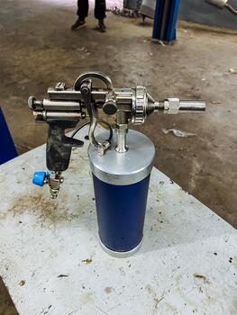 workshop bench with lubrication tool, chrome nozzle pressure trigger for lubrication, mobilized lubricant spray device featuring pressure trigger and chrome nozzle for detailed lubrication photo