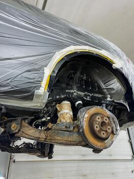 vehicle brake repair, rusty rotor and hub being repaired by technician in workshop setting, automotive service technician replacing brake components on lifted vehicle with visible rust and tools photo