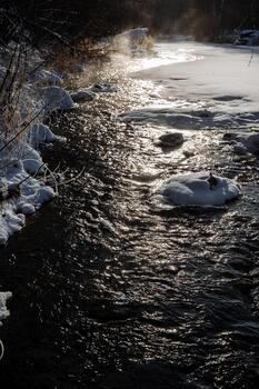cold winter stream with ice, chilly winter rapids with floating ice and slippery stones surface, gloomy frozen stream rushing beneath stormy winter sky with icy patches and smooth stones photo