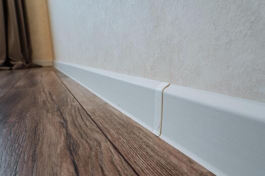 achieving smooth connections through careful sealing and precise fitting techniques, ensuring seamless integration of baseboard and flooring with subtle caulking and meticulous joint preparation photo