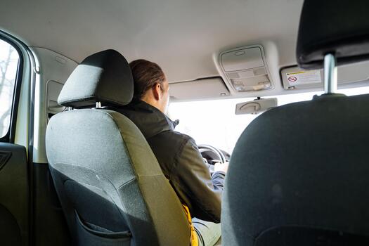 driver looks at cellphone, motorist using mobile device while engaged in conversation outdoors, driver distracted by phone while discussing route information in urban environment photo