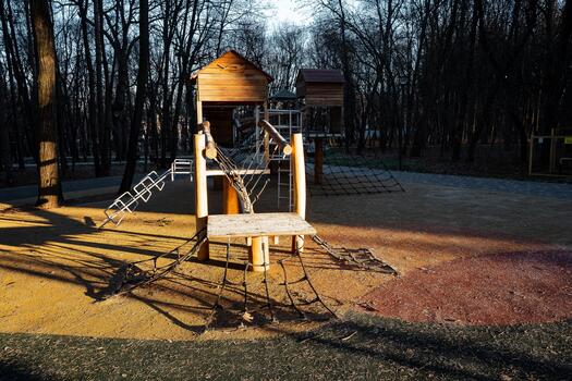 golden hour playground with shadows cast, serene park scene featuring empty slides and warm sunlight, tranquil park setting showing vacant play towers with soft evening illumination photo