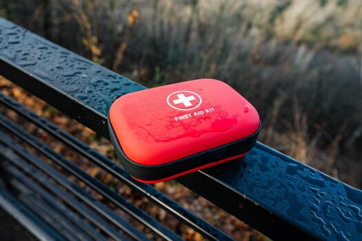 Emergency kit overview, First aid package with reflective features, Compact medical supplies container for quick access, Red emergency response kit with reflective droplets photo