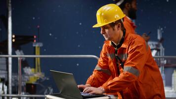 orolig miljö- ingenjör svettas och arbetssätt under spänning på ett offshore olja rigg, kämpar till säkerställa effektiv extraktion av petroleum och naturlig gas. havs operationer. kamera b. video