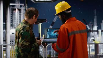 Military soldier and engineer on offshore oil rig uses deep learning software to monitor natural gas extraction, analyzing drilling operations. Ocean ecosystem exploit. Camera B. video