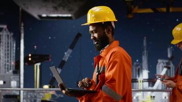 svart offshore ingenjör övervakning olja rigg plattform drift använder sig av bärbar dator, säkerställa effektiv industriell aktivitet till främja naturlig gas och petroleum extraktion. pumpning fossil bränslen. kamera b. video