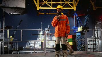 arbetstagare på olja plattform talar genom radio enheter till inspektera borrning system för efterlevnad, hantering olja och gas extraktion från de havs ekosystem för industriell Resurser. kamera a. video