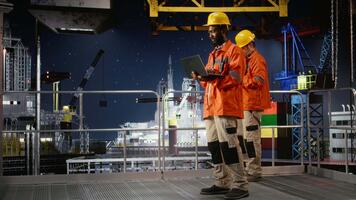 svart offshore ingenjör övervakning olja rigg plattform drift använder sig av bärbar dator, säkerställa effektiv industriell aktivitet till främja naturlig gas och petroleum extraktion. pumpning fossil bränslen. kamera a. video