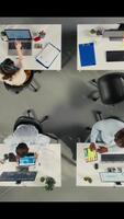 vertical topo baixa Visão do colegas dentro multinacional companhia escritório discutir estratégia, gráficos e análise. trabalhos equipe coordenadas progresso, intuições e documentação para Melhor resultados. Câmera uma. video