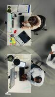 vertical topo baixa Visão do empregados equipe discutir o negócio intel e desempenho dentro escritório. multinacional companhia funcionários membros avaliações relatórios, previsões e diagramas para alinhar estratégia. Câmera uma. video