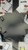 vertical topo baixa Visão ampliação Fora do colegas de trabalho analisando o negócio dados e Métricas durante relatório partilha sessão dentro sala de reuniões. profissional trabalhos equipe discutir previsão e gestão percepções. Câmera uma. video
