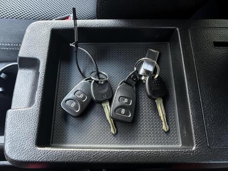 Multiple car keys resting in a storage tray inside a vehicle console during a sunny day in a suburban area photo